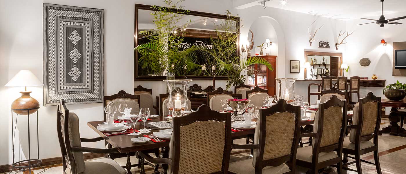 The dining room with a long laid table, dark wood chairs and white walls